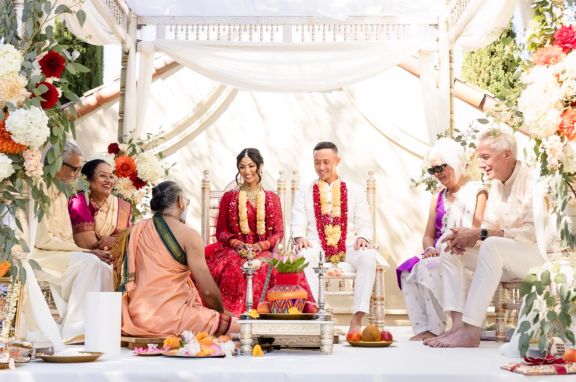 Couple seated during a traditional Indian wedding ceremony under a decorated mandap