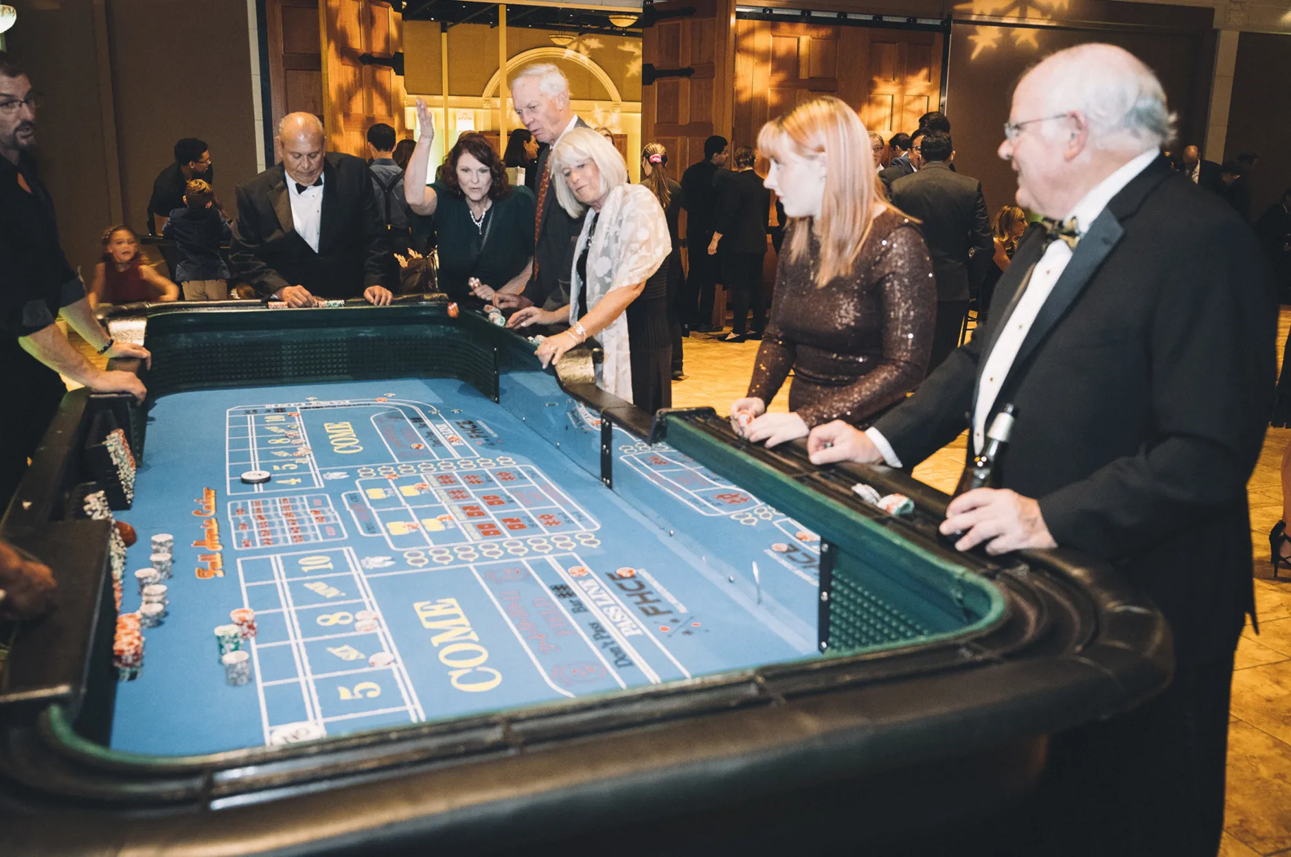 Guests in formal attire playing craps at a casino-themed corporate gala