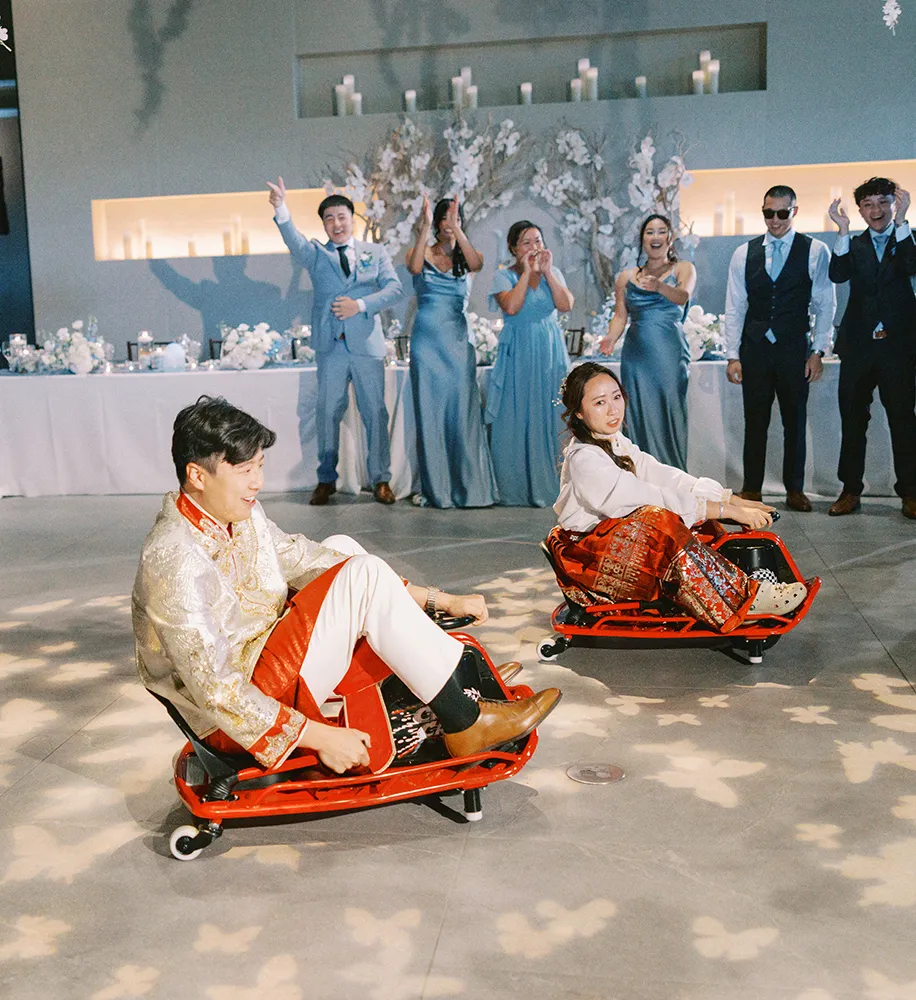 Bride and groom racing on bumper cars while the wedding party cheers them on