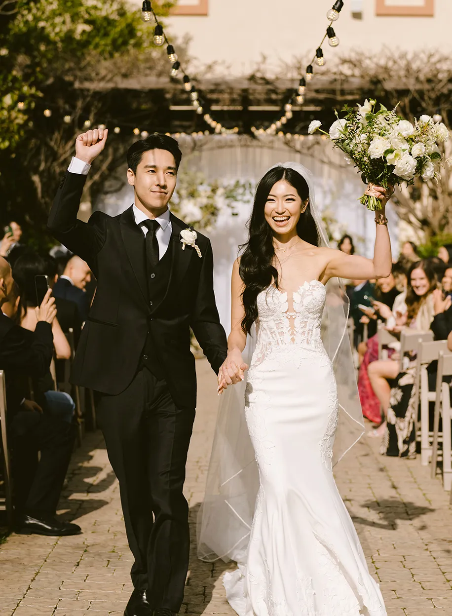 Newlyweds cheering as they walk back down the aisle after their ceremony