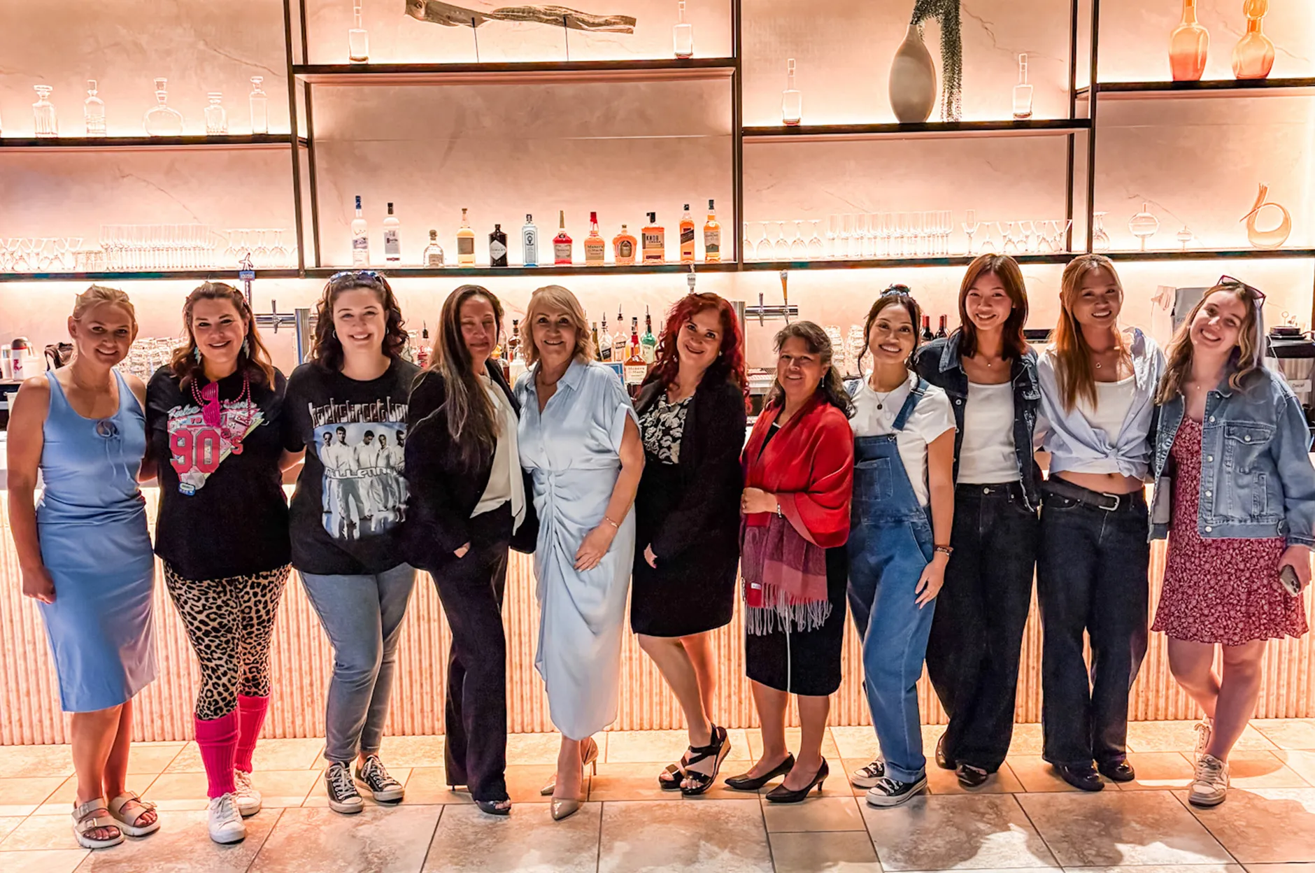 Group of team members lined up for a photo in front of the venue bar with backlit shelving