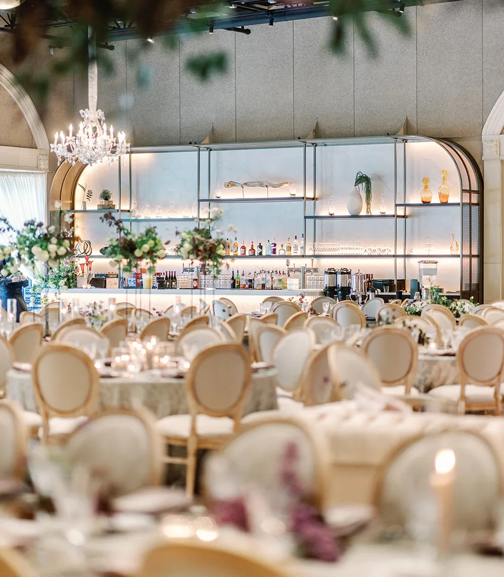Redesigned Casa Real bar and reception hall with crystal chandeliers, arched glass shelving, and elegant cream seating