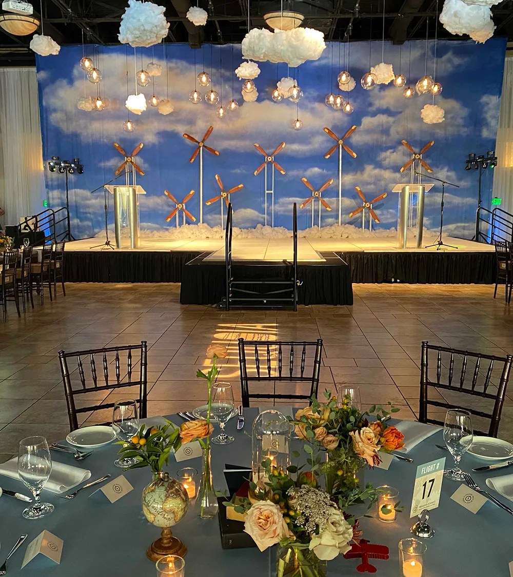 Corporate event venue with a wind energy-themed stage design and decorated banquet tables
