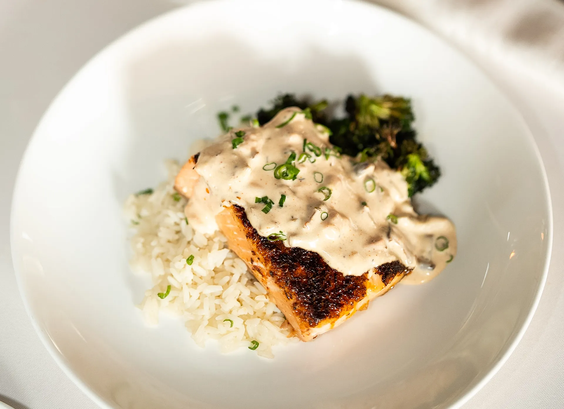 Pan-seared salmon with cream sauce served over rice and broccoli