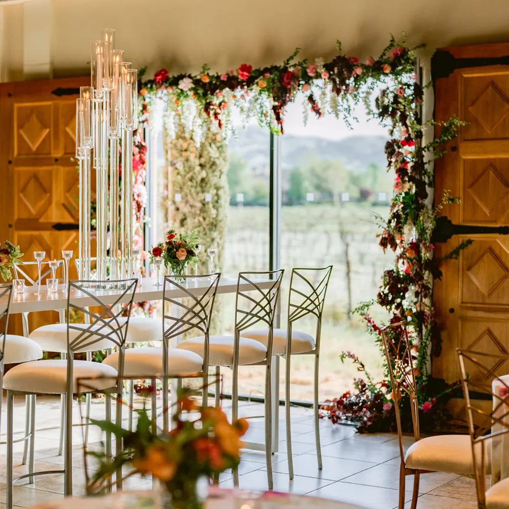 Crystal chandelier and floral arch framing a vineyard view through floor-to-ceiling windows