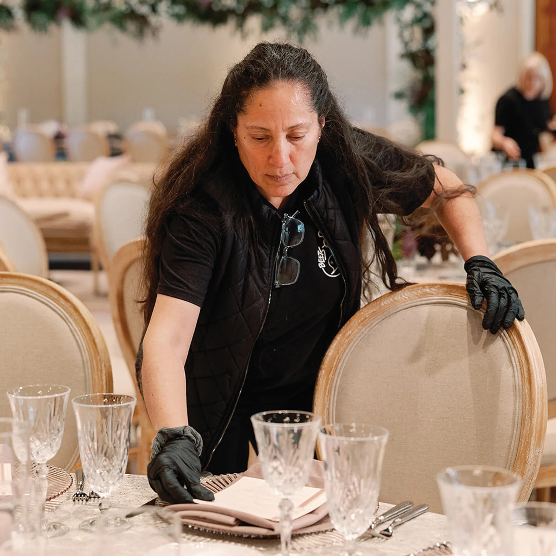 Team member in black setting a formal place setting with crystal glassware in the banquet hall